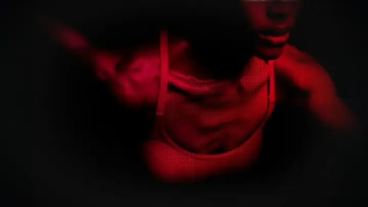 A bust of a fit African-American woman in red light showing movement